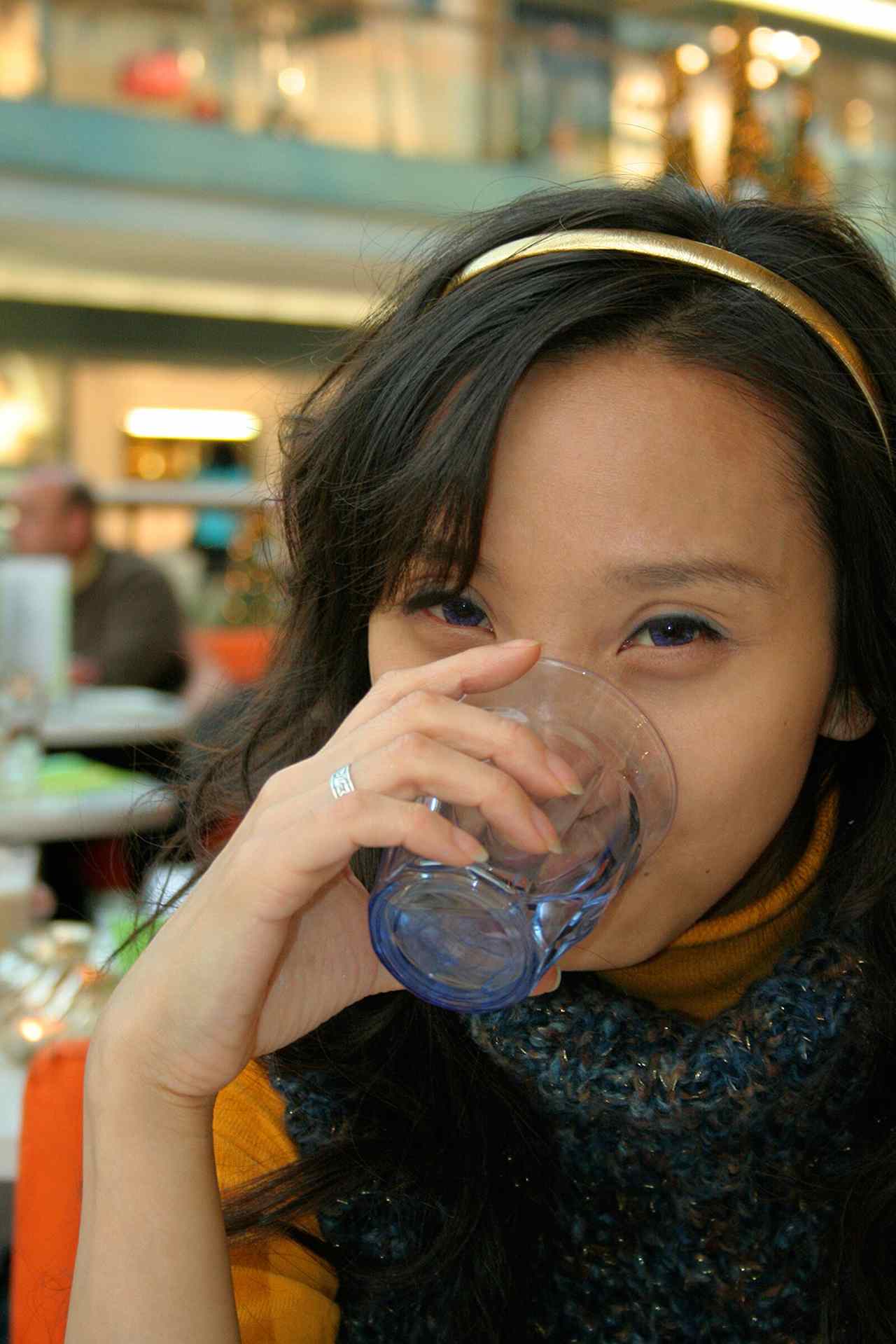 Seseorang minum segelas air putih, menggambarkan pentingnya hidrasi untuk menjaga produksi air liur dan mencegah mulut kering penyebab bau mulut