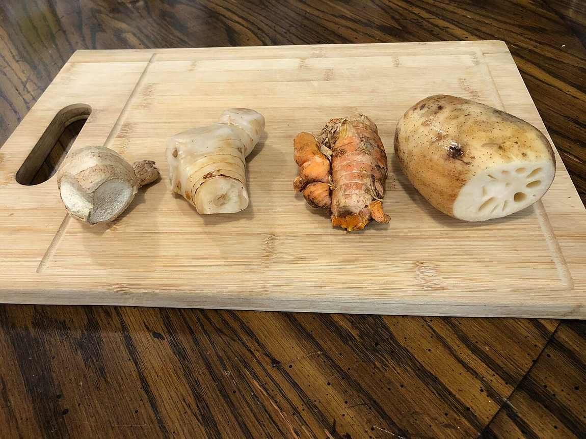 Jahe, lengkuas, kunyit, dan akar teratai di atas talenan kayu, bahan alami yang umum digunakan untuk membantu meredakan gejala asam lambung