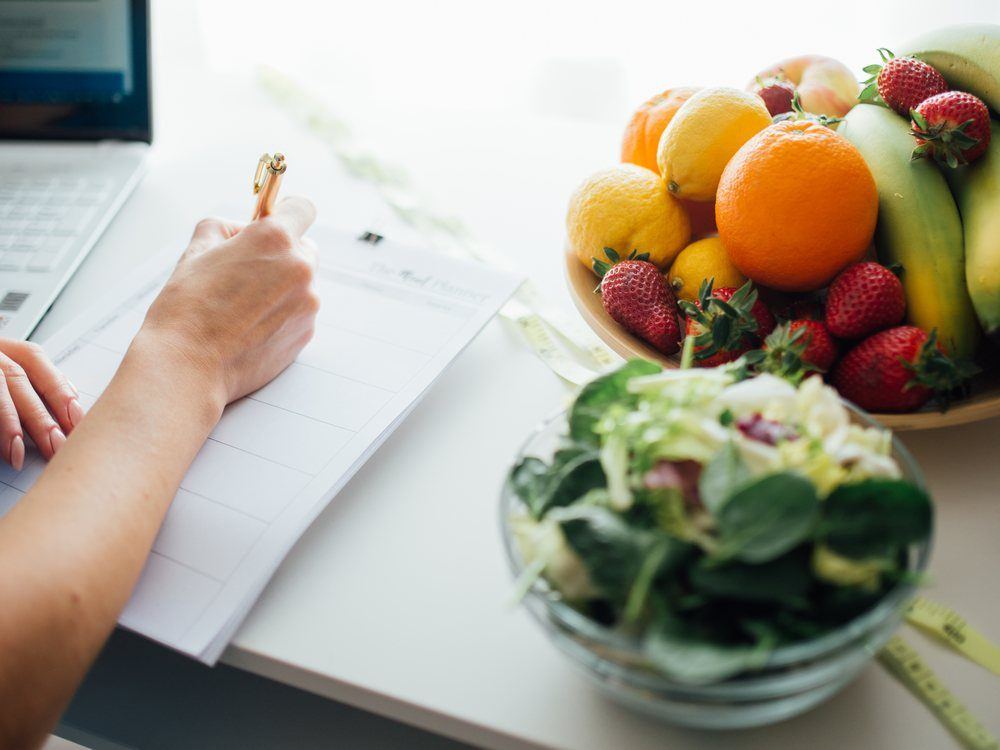 Seseorang menyiapkan menu makan sehat dengan sayur dan buah segar di dapur