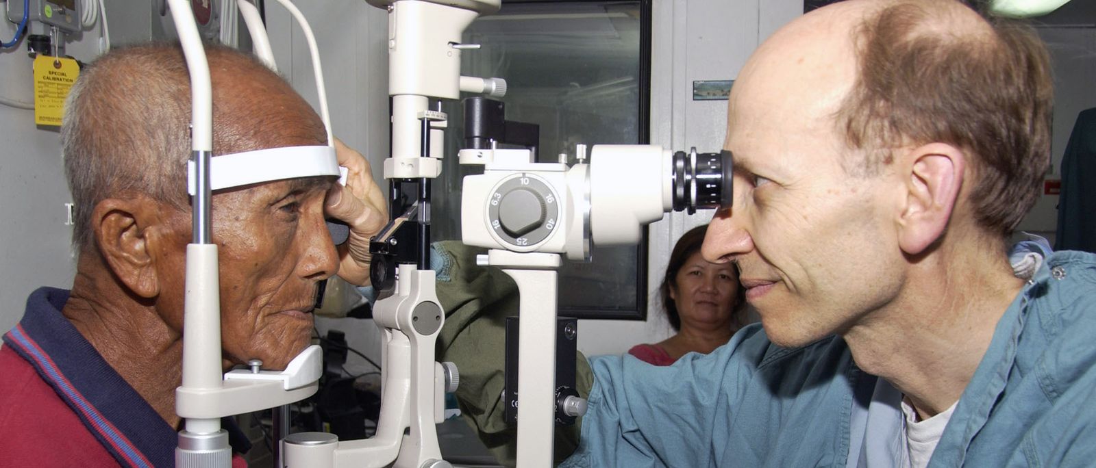 Dokter memeriksa mata pasien katarak menggunakan slit lamp