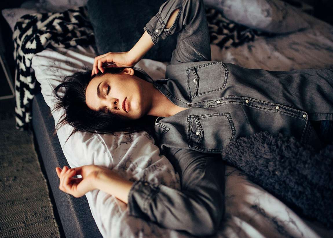 Wanita beristirahat dengan mata tertutup di atas tempat tidur yang nyaman