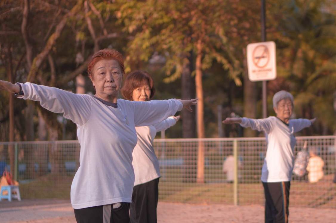 Sekelompok lansia melakukan tai chi bersama di taman pada pagi hari
