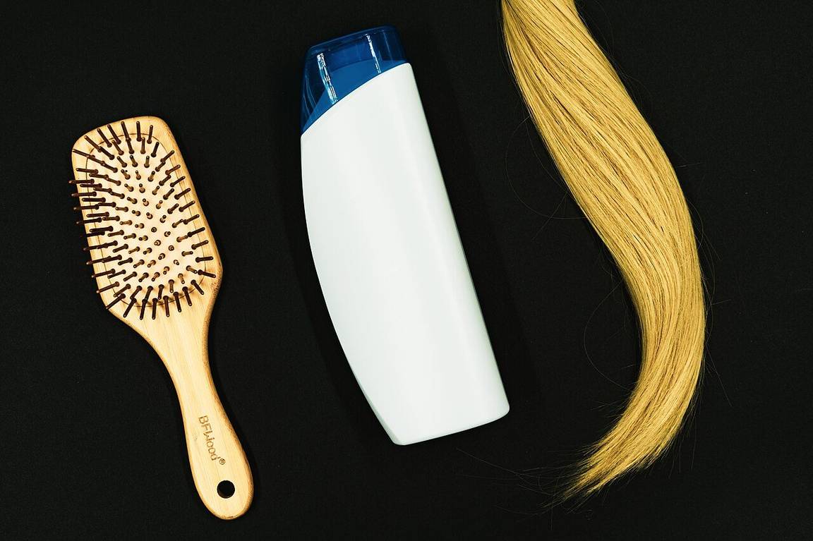 Sikat rambut, botol sampo, dan helai rambut yang menjadi bagian dari rutinitas perawatan rambut