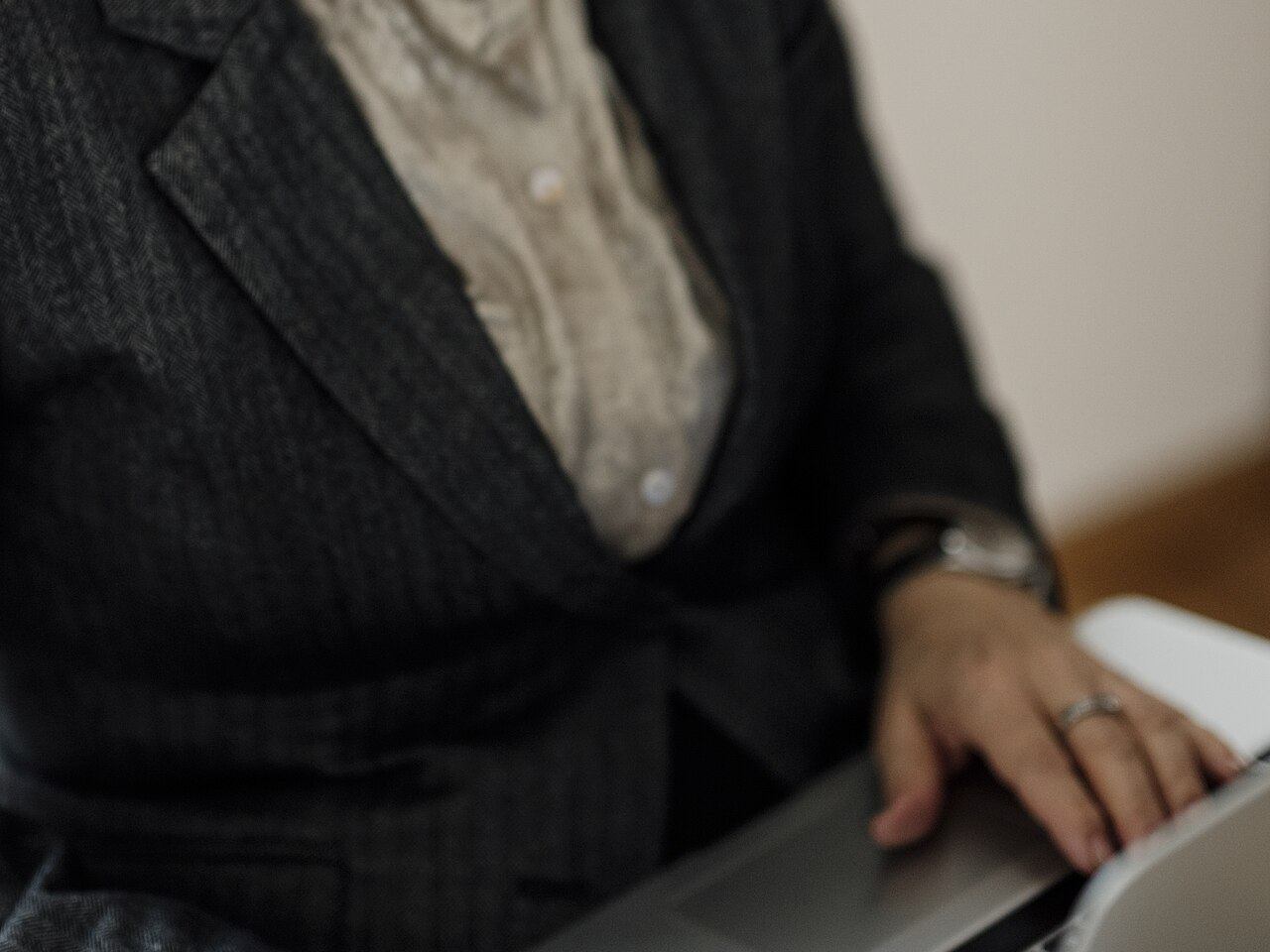 Wanita berdiri di ruang kerja modern sambil menggunakan laptop, mencerminkan tantangan menjaga fokus di tengah rutinitas kerja